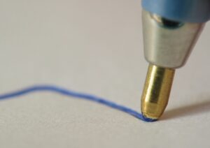 Close-up of ballpoint pen drawing a blue line on paper