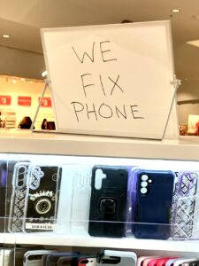 "We fix phone" sign atop a seller's case of smartphone covers.